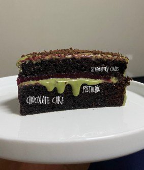 A slice of dark chocolate cake with a bright pistachio layer running through it.