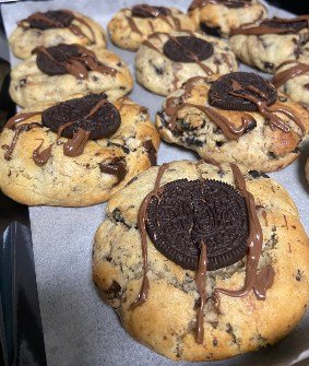 A tray of thick cookies stuffed with chocolate, finished with a dark biscuit on top.